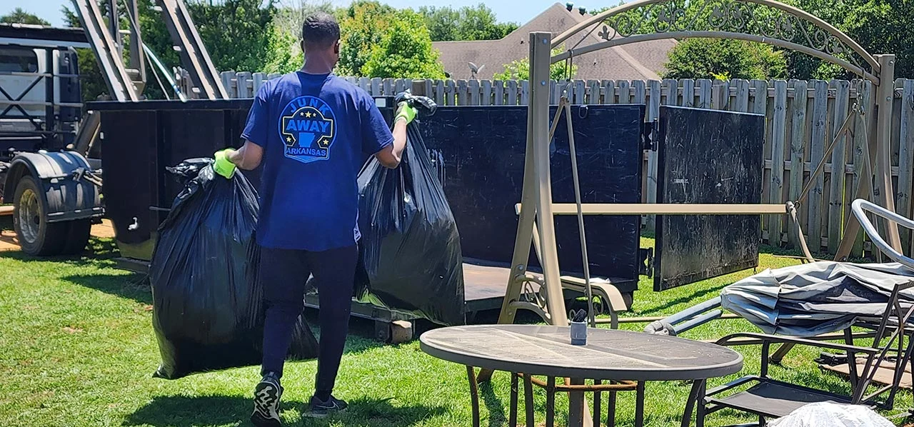 Junkaway worker throwing a garbage bag into a dumpster