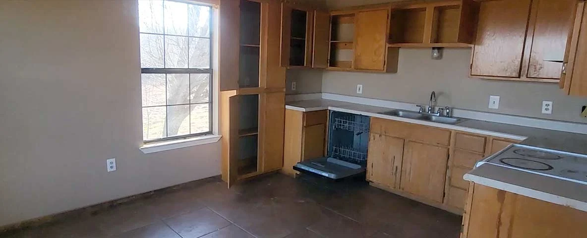 Kitchen area completely cleaned out with open and empty cabinets