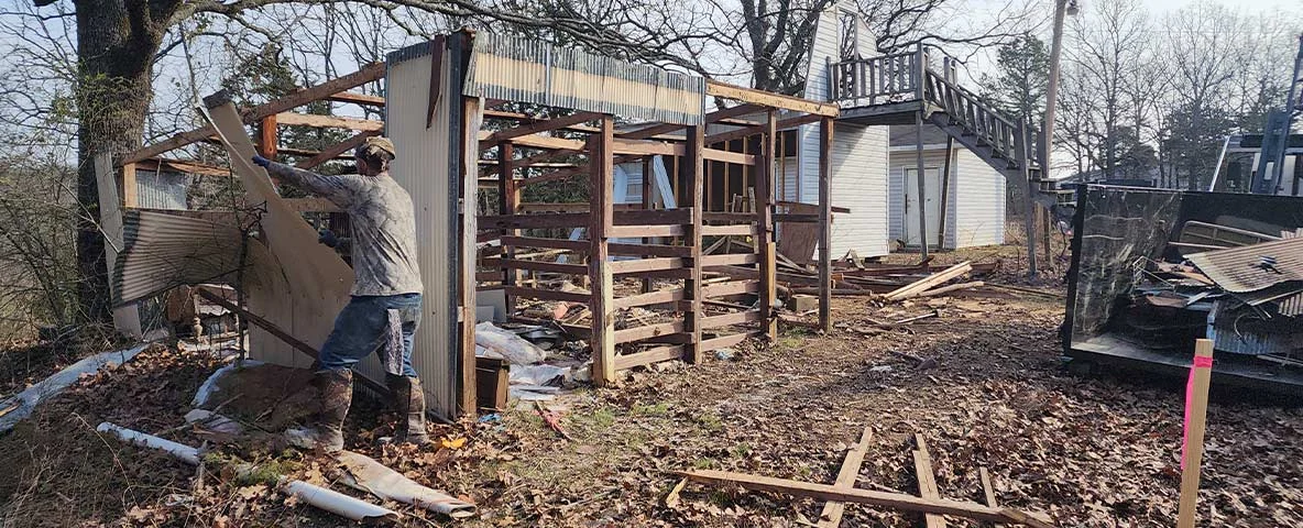 Worker tearing down old shed