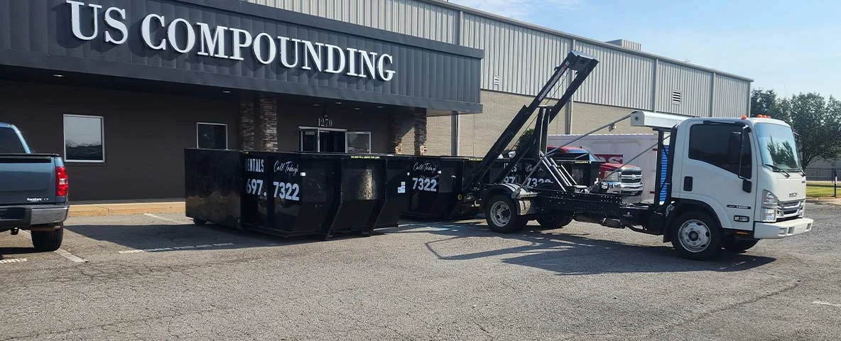 Truck dropping off dumpsters in front of office